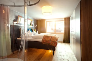 Un dormitorio con cama, ducha, armario y ventana con cortinas.