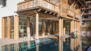 A wooden building with a pool, large windows, and balconies. - Raffl´s Tyrol Hotel (Sankt Anton am Arlberg)