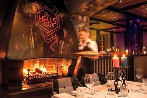 A restaurant with a fireplace, a neon sign, and a bar area. - Raffl´s Tyrol Hotel (Sankt Anton am Arlberg)