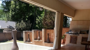 An outdoor patio area with a pool, a grill, and a seating area with a table and chairs. - The Munday Bed & Breakfast (Germiston)