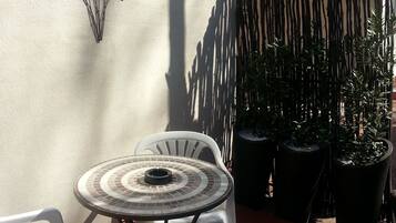 A patio with a round table and two chairs, a decorative wall, and a tiled roof.