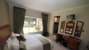 A hotel room with a large bed, a desk, a TV, and a window with curtains. - The Munday Bed & Breakfast (Germiston)