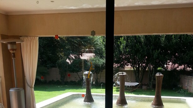 A patio area with a seating arrangement, a decorative fountain, and a view of a garden. - The Munday Bed & Breakfast (Germiston)