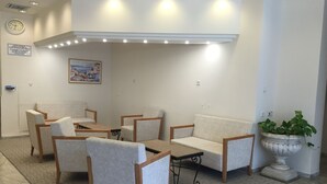 A modern living room with a sofa, chairs, a coffee table, and a potted plant. - Berger Ultra Orthodox Hotel (Tiberias)