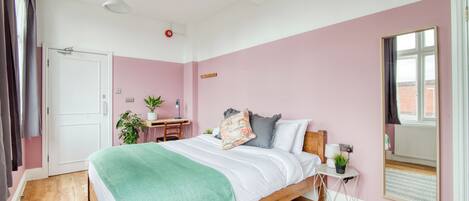 A bedroom with a bed, bedside table, and a window.