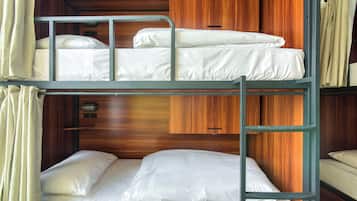Habitación con literas, paneles de madera y un mueble pequeño.