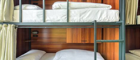 A bunk bed room with wooden paneling and a small cabinet.