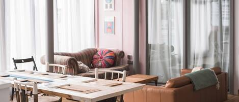 A cozy living room with a wooden table, leather sofa, and a colorful pillow.