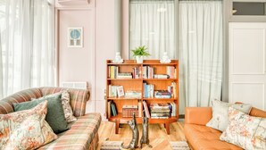 A living room with a striped sofa, a wooden bookshelf, and a cat statue. - Malacuna Birmingham (Birmingham)