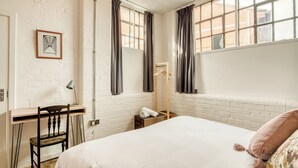 A room with a bed, a desk, a chair, a hanging coat rack, and a window with curtains. - Malacuna Birmingham (Birmingham)