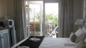 A hotel room with a bed, a TV, a desk with a computer, and a view of the outside. - La Boheme Bed and Breakfast (Plettenberg Bay)