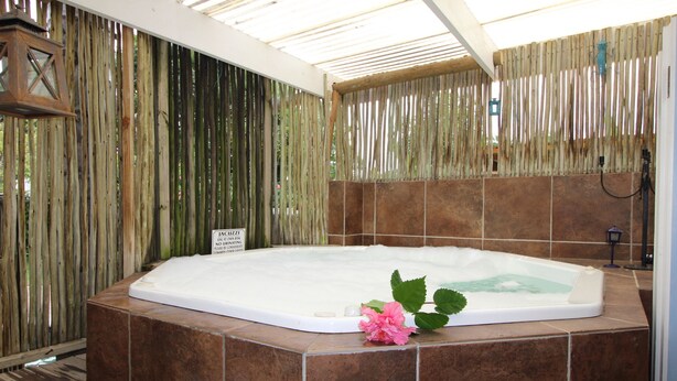 A hot tub with a wooden fence and a sign, surrounded by tiled walls. - La Boheme Bed and Breakfast (Plettenberg Bay)