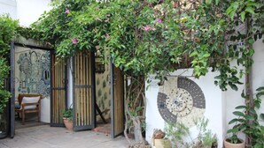 A courtyard with a wooden gate, a bench, and potted plants. - La Boheme Bed and Breakfast (Plettenberg Bay)