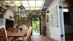 A wooden dining table with chairs, a hanging lantern, and a rustic brick floor. - La Boheme Bed and Breakfast (Plettenberg Bay)