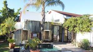 A private pool area with a small hot tub, surrounded by a wooden fence and potted plants. - La Boheme Bed and Breakfast (Plettenberg Bay)