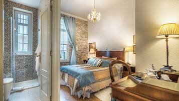A bedroom with a bed, bedside tables, a chandelier, and a window with curtains.