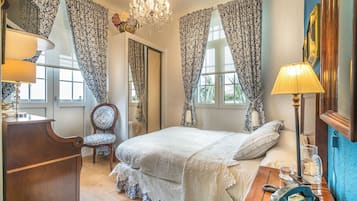 Un dormitorio con una cama grande, un aparador de madera, una silla y un escritorio con lámpara y teléfono.