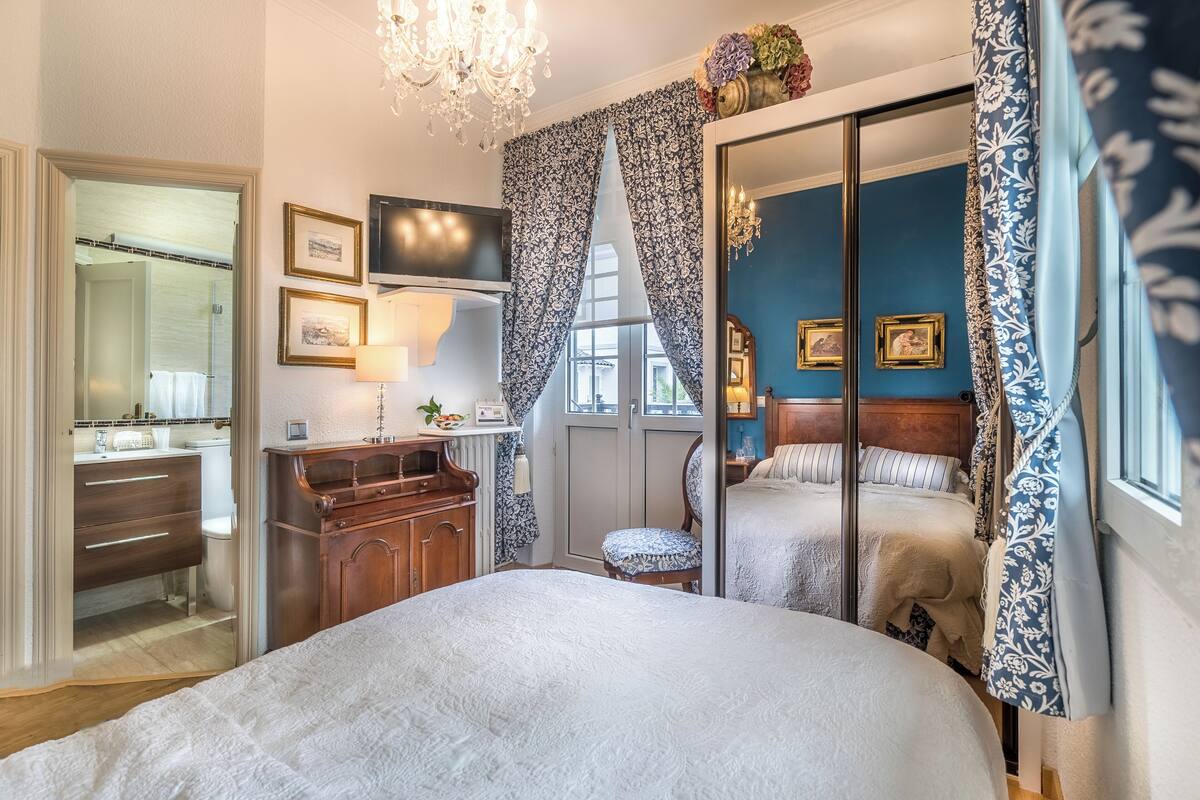 A bedroom with a large bed, a dresser, a television, and a mirror.