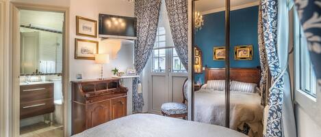 A bedroom with a large bed, a dresser, a television, and a mirror.
