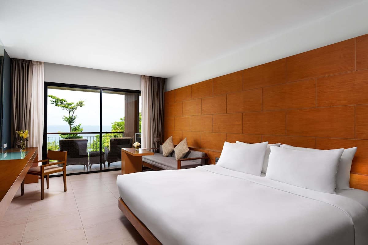 Een hotelkamer met een groot bed, een bureau en een balkon met uitzicht.