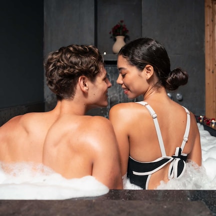 A couple in a hot tub with a candle and flowers.