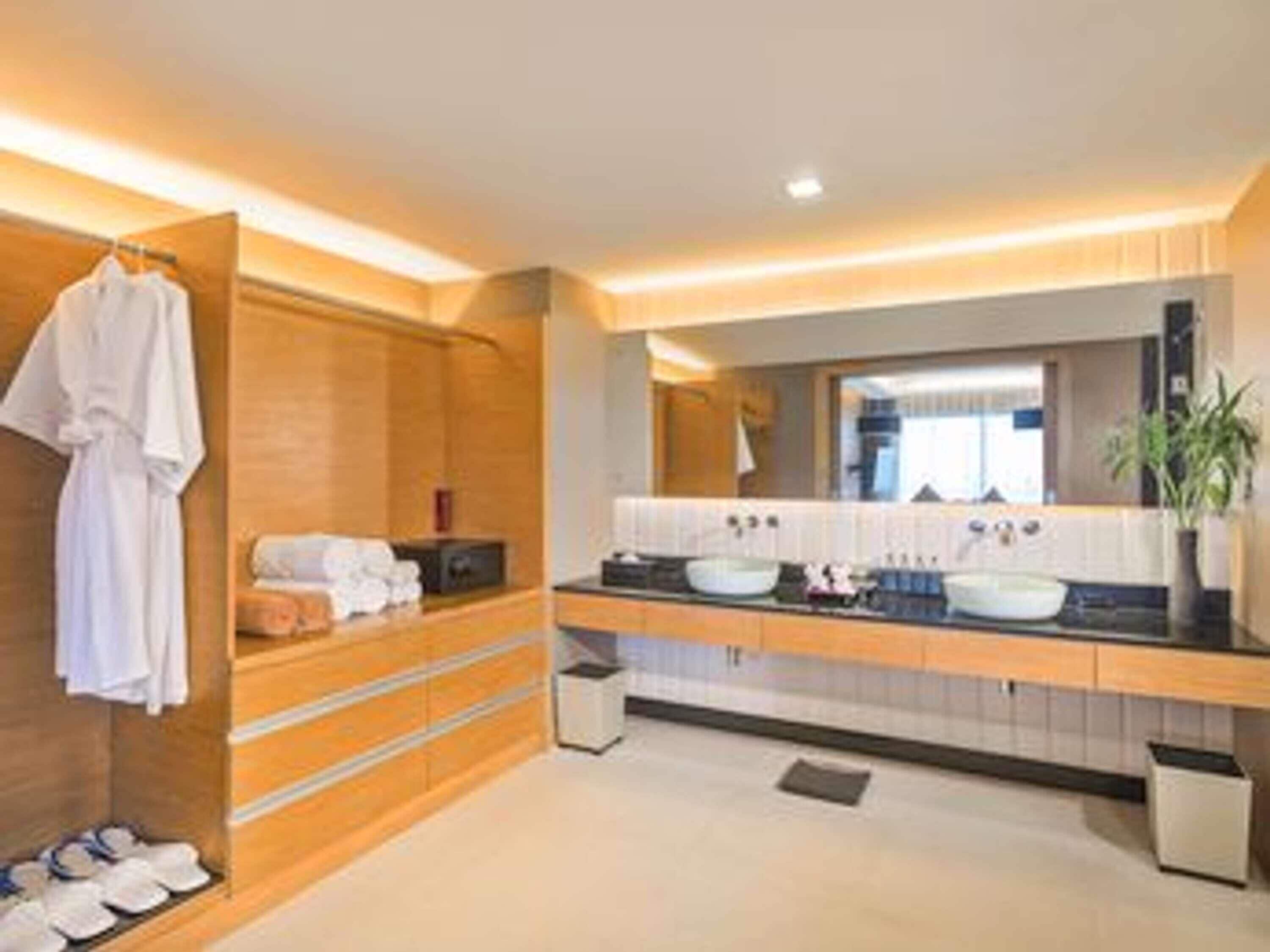 Un baño moderno con muebles de madera, un espejo grande y dos lavamanos.