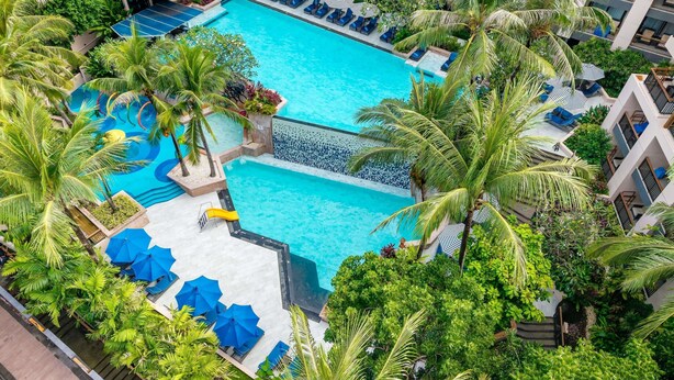Ein großer Pool, umgeben von Palmen und blauen Liegestühlen.