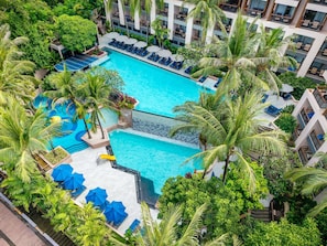 A large swimming pool surrounded by palm trees and blue lounge chairs.