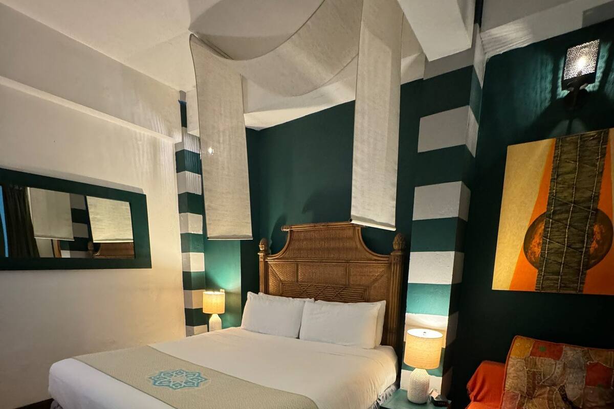 Ein Schlafzimmer mit einem großen Bett, einem Nachttisch, einem Beistelltisch, einem Sessel und einem am Wand montierten Fernseher.