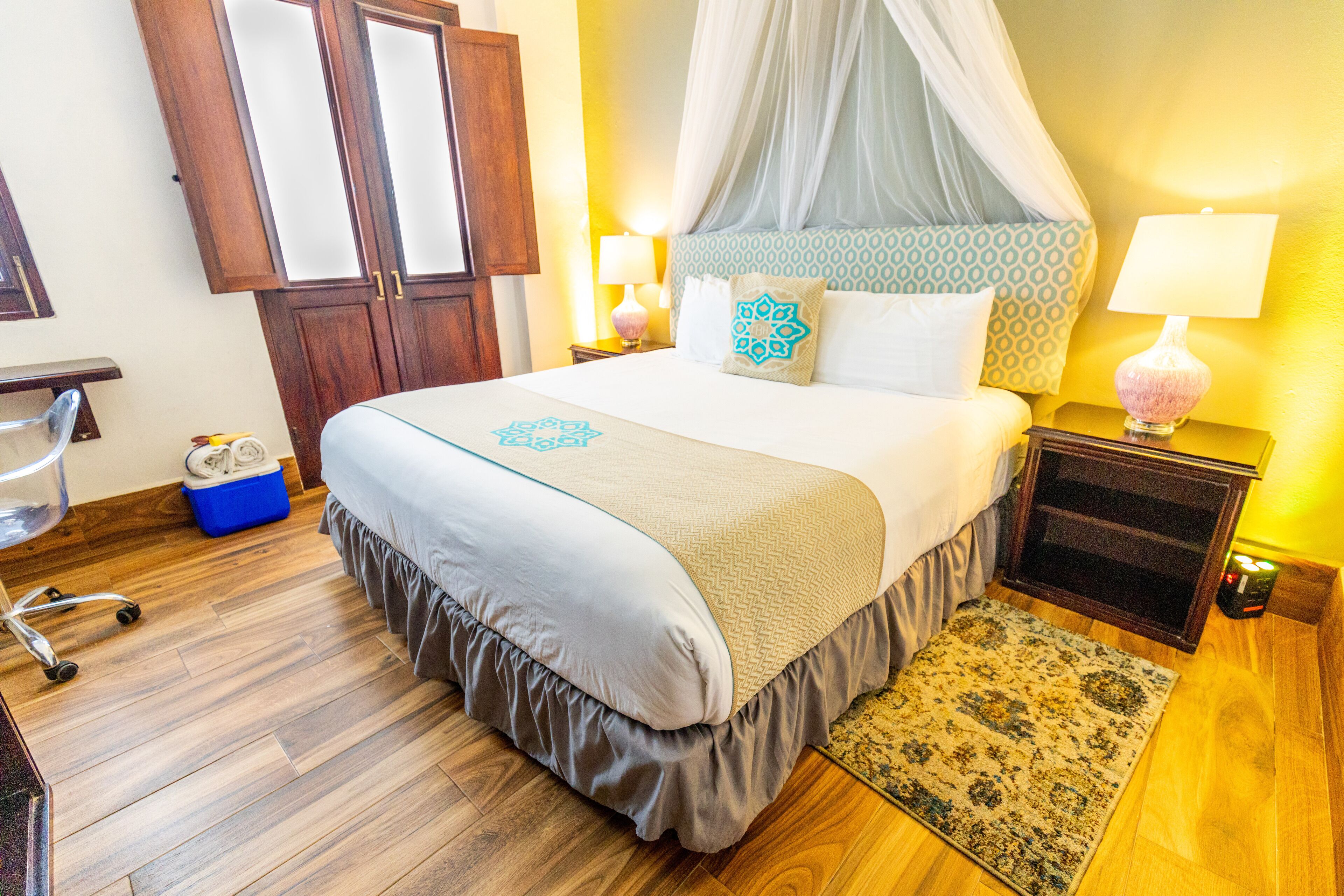A bedroom with a bed, a nightstand, a lamp, a chair, and a wardrobe.