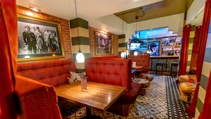 A restaurant with red booths, a wooden table, and a patterned floor. - CasaBlanca Hotel (San Juan)