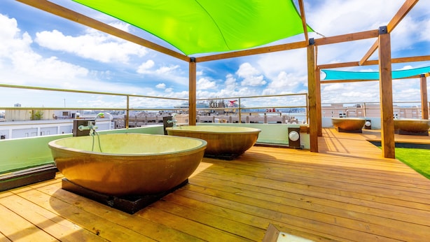 A rooftop deck with large tubs and a wooden deck, overlooking a cityscape. - CasaBlanca Hotel (San Juan)