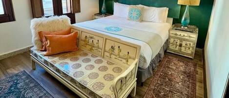 A bedroom with a bed, bedside tables, a mirror, and a hanging canopy.