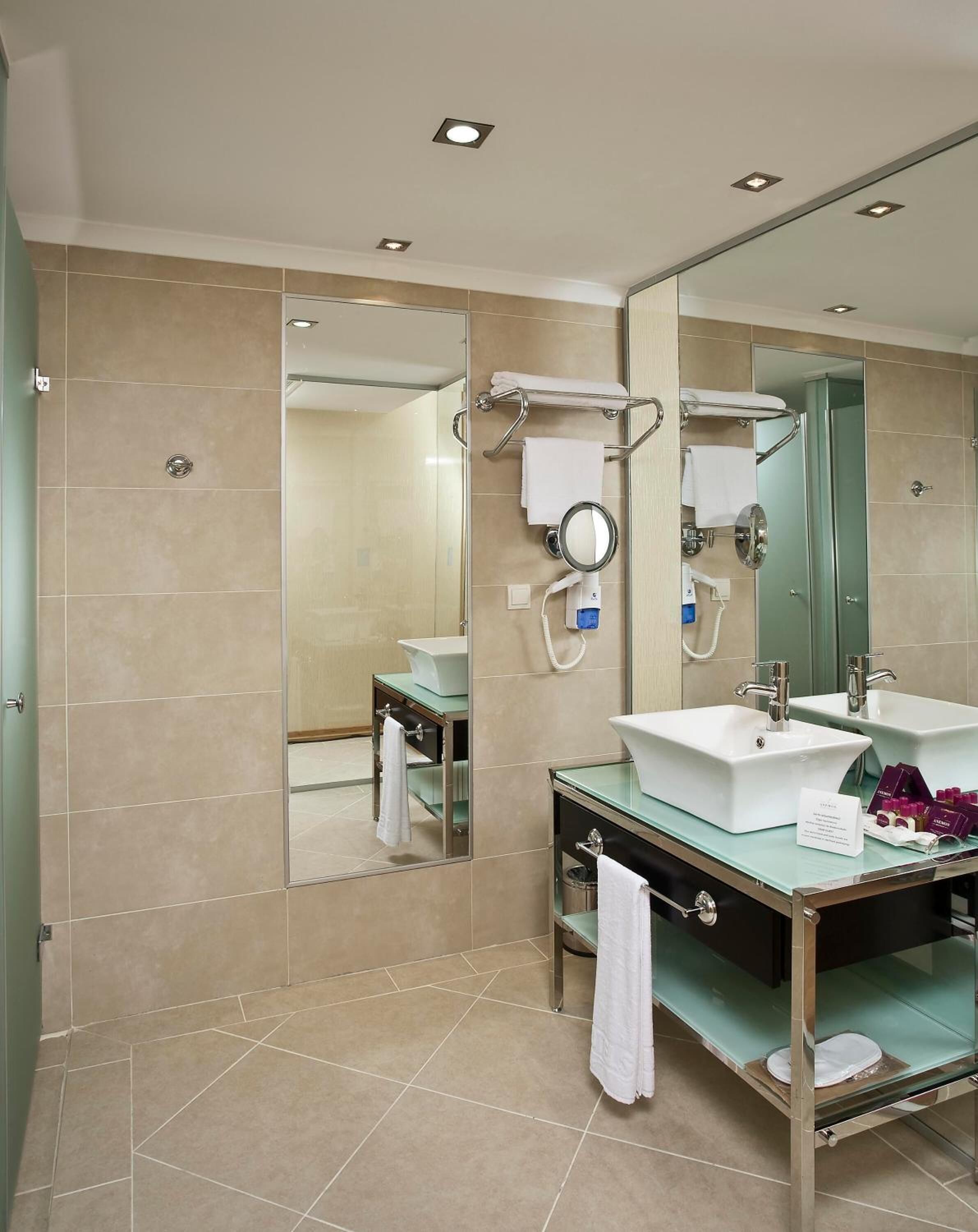 A modern bathroom with two sinks, a large mirror, and a glass shower enclosure.