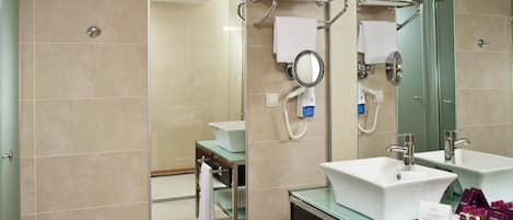 Un baño moderno con dos lavamanos, un espejo grande y cabina de ducha de vidrio.