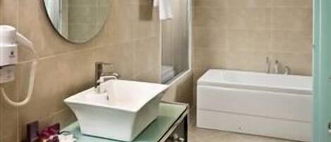 Un baño moderno con un lavabo grande, espejo y bañera.