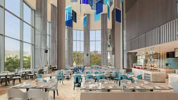 A spacious dining area with high ceilings, large windows, and modern furniture.