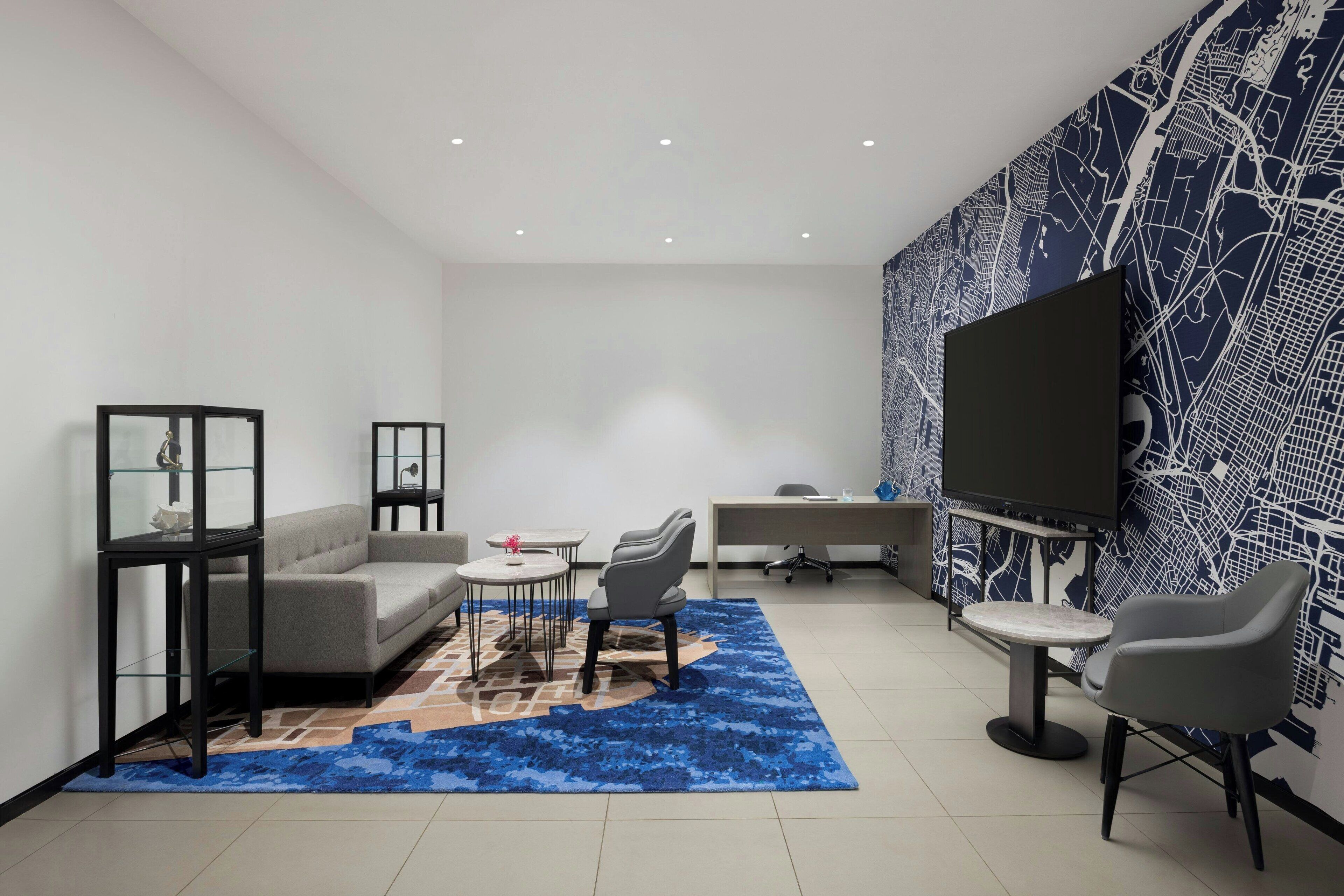 A modern living room with a sofa, chairs, a coffee table, a TV, and a patterned wall.
