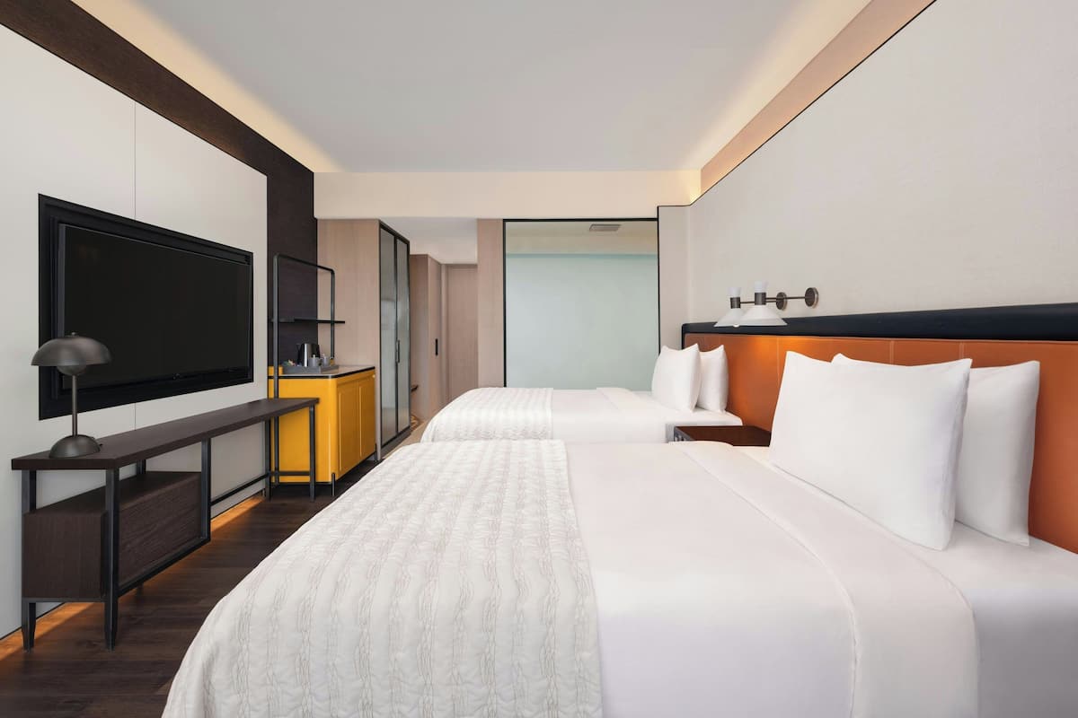 Une chambre d’hôtel moderne dotée d’un grand lit, d’un bureau, d’une télévision à écran plat et d’un mini-bar.