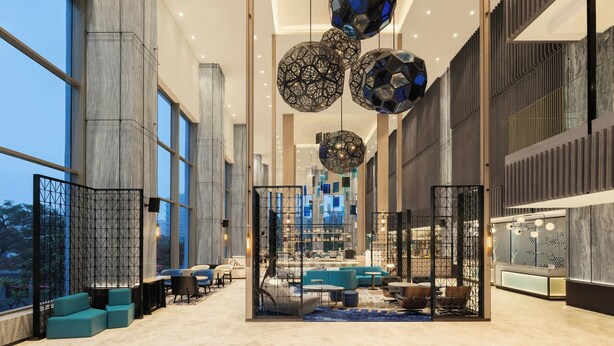 Een ruime lobby met hoge plafonds, grote ramen en moderne zithoekjes.