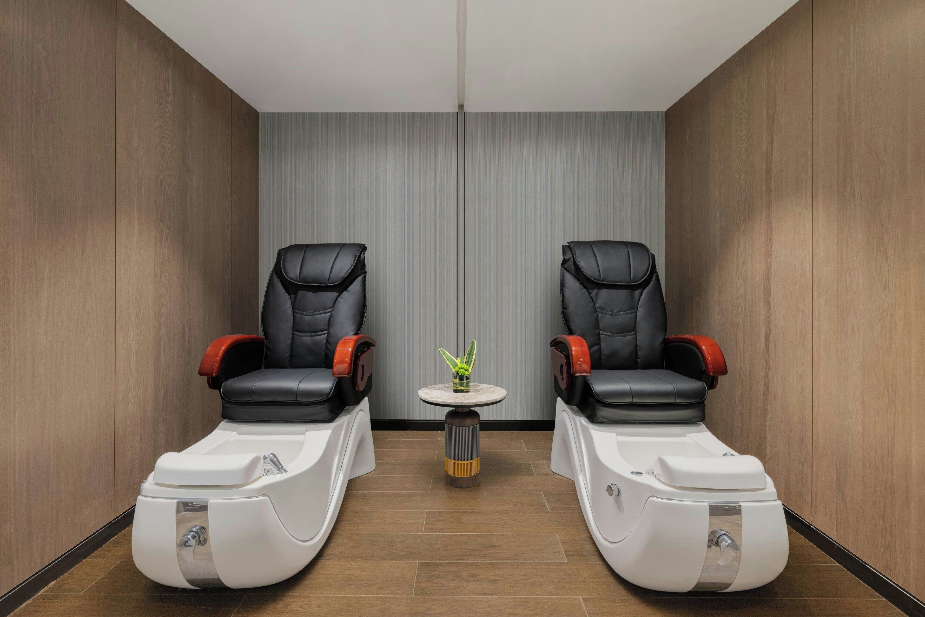 A room with two massage chairs and a small table with a plant.