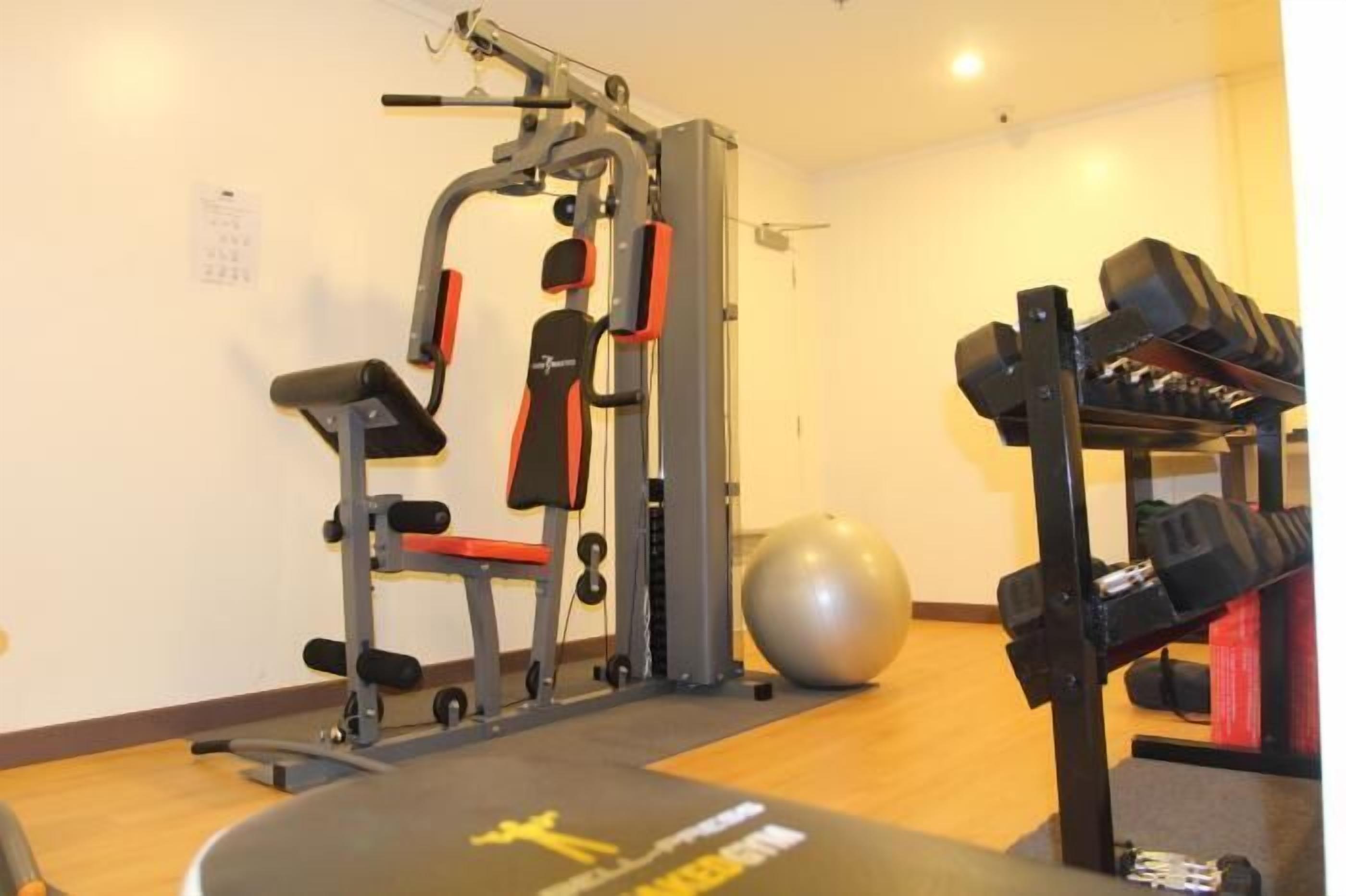 Un gimnasio con equipo de ejercicio, un soporte para pesas y una colchoneta de yoga.