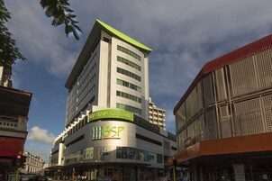 Un edificio de varios pisos con señalización de BSP Suva Central y un área comercial en la planta baja.