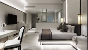 A modern bedroom with a large bed, a desk, a chair, and a TV. - Chanalai Romantica Resort Kata Beach - Adults Only (Karon)