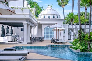 Una piscina al aire libre, sombrillas, sillones reclinables de piscina