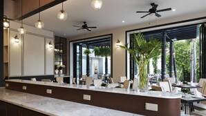 Un restaurante moderno con mostrador de mármol, ventiladores de techo y amplias ventanas.