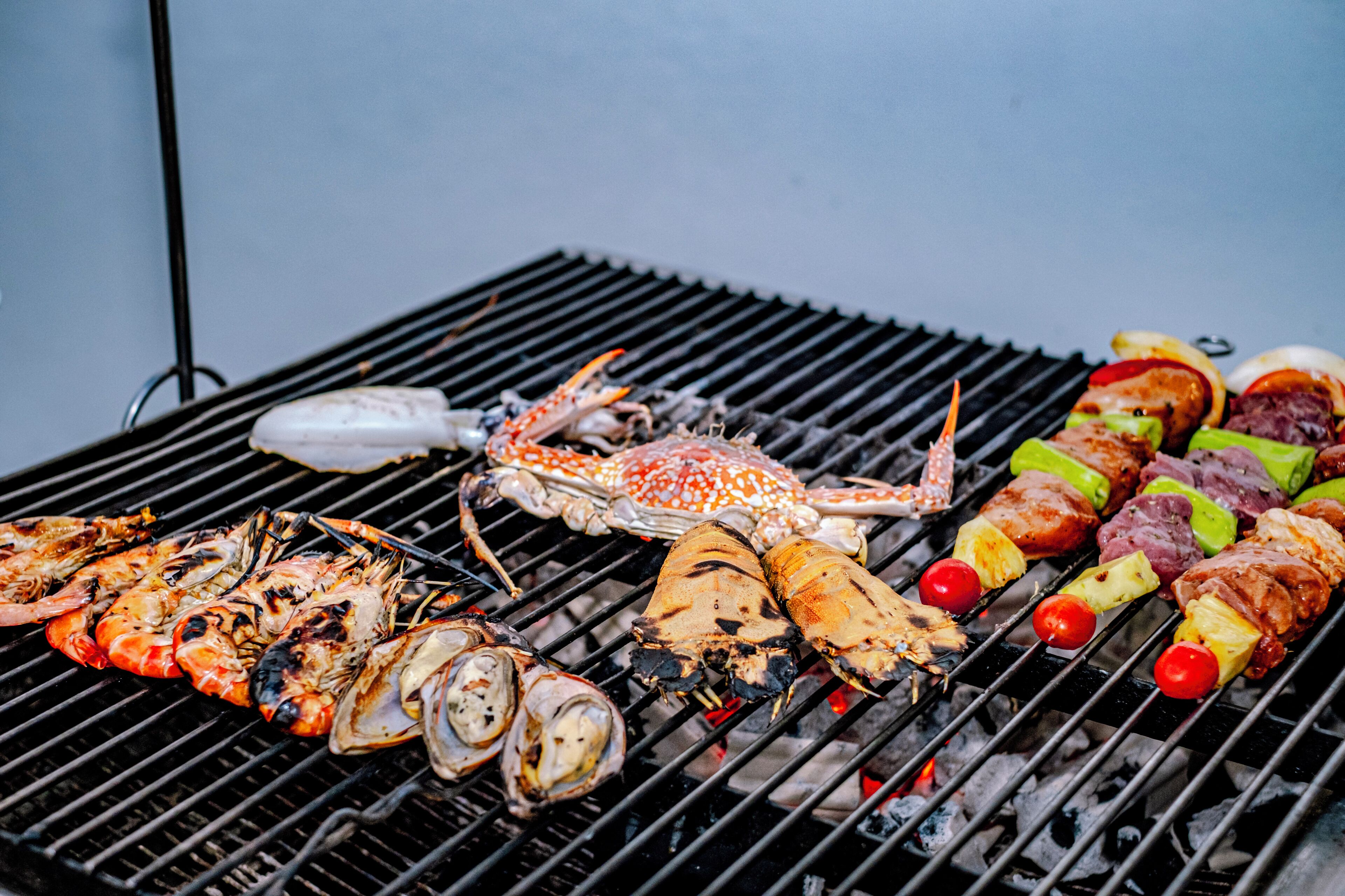 A grill with various seafood and meats being cooked.
