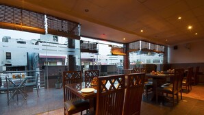 Un restaurante con mobiliario de madera, ventanas amplias y vistas a edificios.