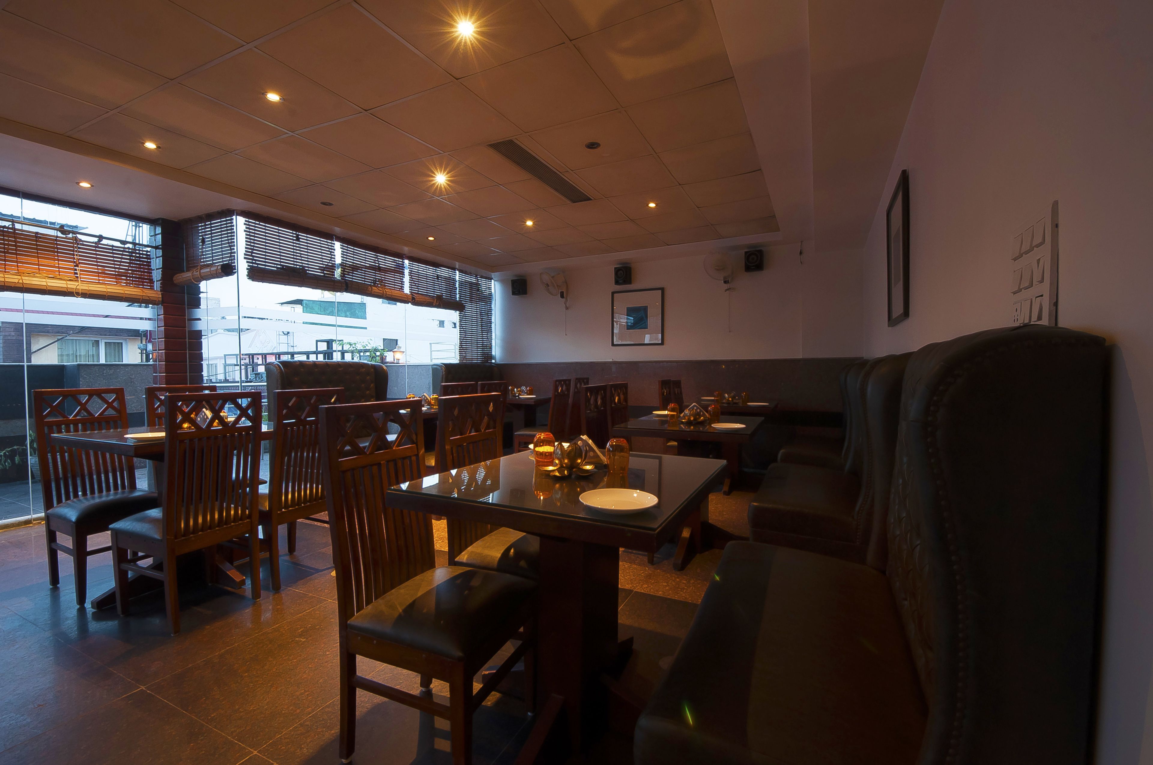 Un restaurant dont le mobilier, les tables et les chaises sont en bois, et qui offre une vue sur les bâtiments environnants.