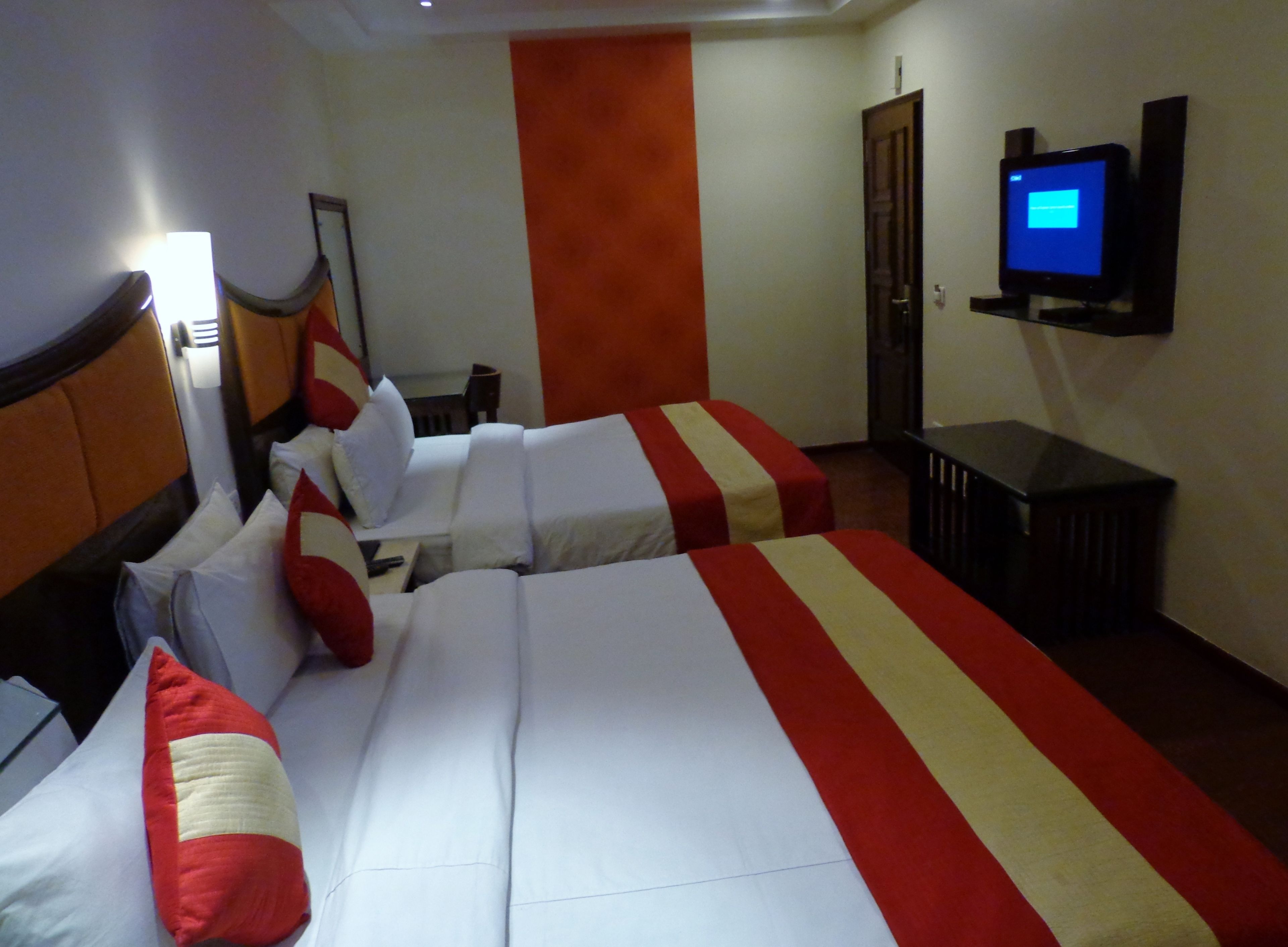 Habitación de hotel con dos camas, televisión y escritorio.